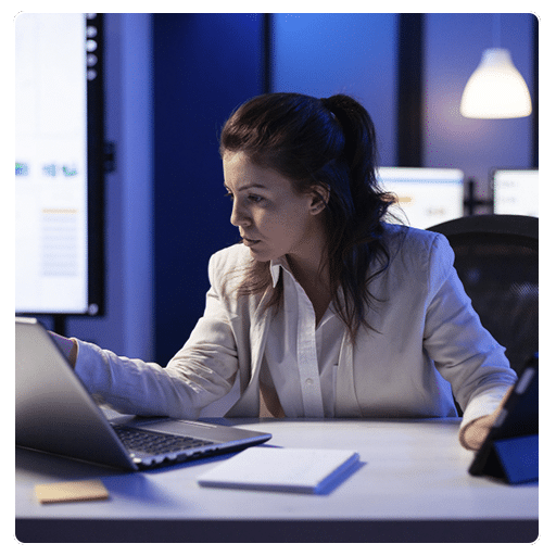 Profissional analisando dados de SEO no computador em ambiente corporativo noturno.